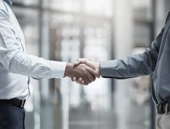 Business professionals shaking hands in a corporate office setting, symbolizing partnership and agreement